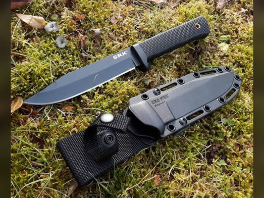 Cold Steel SRK fixed blade knife with its Secure-Ex sheath lying on moss and grass outdoors