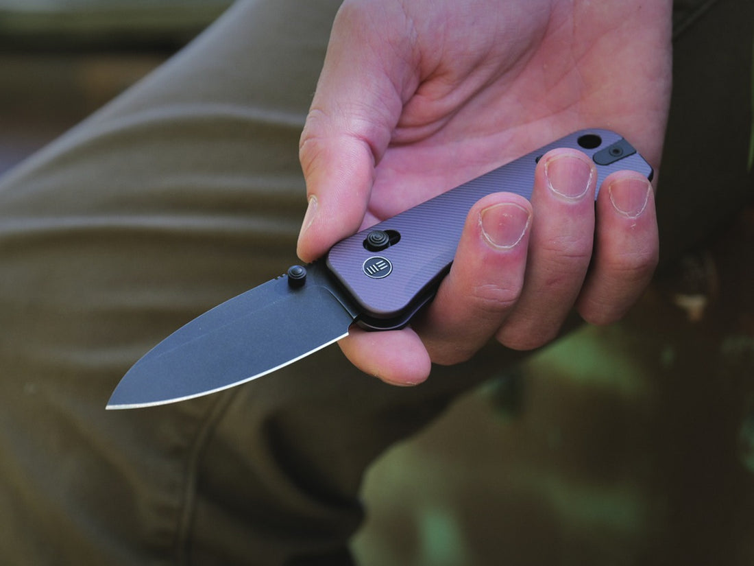 WE Knife Banter 2 folding knife with purple aluminium handle held open in one hand outdoors