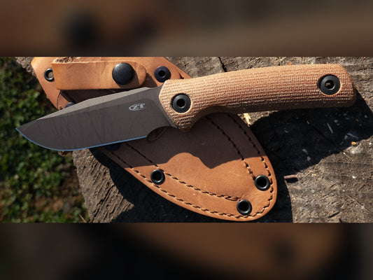 Zero Tolerance 0004 fixed blade with canvas Micarta handle resting on its saddle tan leather sheath outdoors
