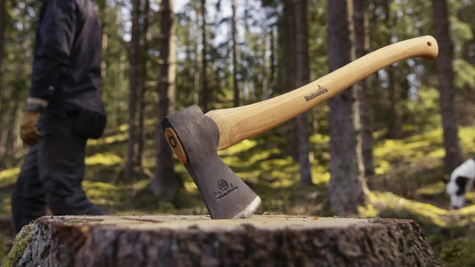 Hand forged Hultafors axe with a hickory handle standing in a spruce stump on a forest clearing